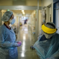 Nao Watarumi (left) waits to remove her protective gear as Junko Yamaguchi does so after emerging from the room of a severely ill COVID-19 patient in the intensive care unit of Itabashi Hospital. | RYUSEI TAKAHASHI
