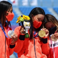 Gold medalist Sakura Yosozumi of Japan celebrates on the podium next to teammate and silver medalist Kokona Hiraki and bronze medalist Sky Brown of Britain.  | REUTERS