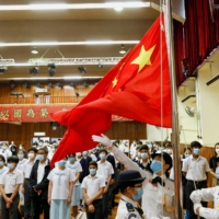 Students attend a flag raising ceremony on National Security Education Day at a secondary school in Hong Kong in April.  | REUTERS 