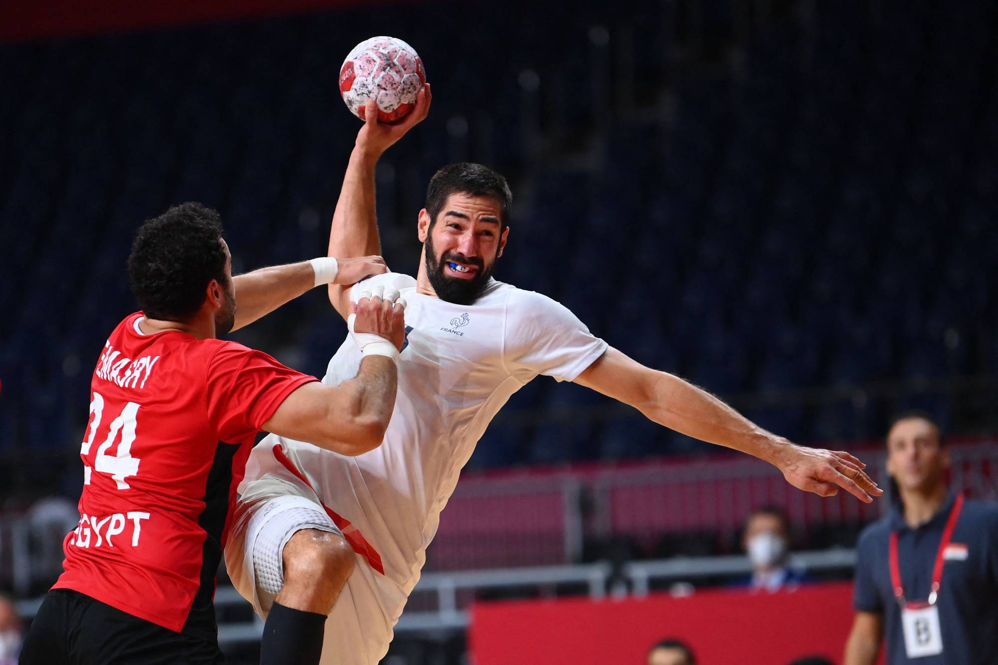 France's Nikola Karabatic (right) is challenged as he shoots during the men's semifinal handball match between France and Egypt. | AFP-JIJI