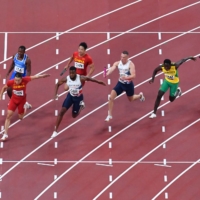 Athletes pass the baton during a leg of the men\'s 4x100m relay final  | AFP-JIJI
