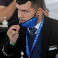 A United Airlines employee swabs his nose for a coronavirus test at MetLife Stadium in East Rutherford, New Jersey, in May. | REUTERS