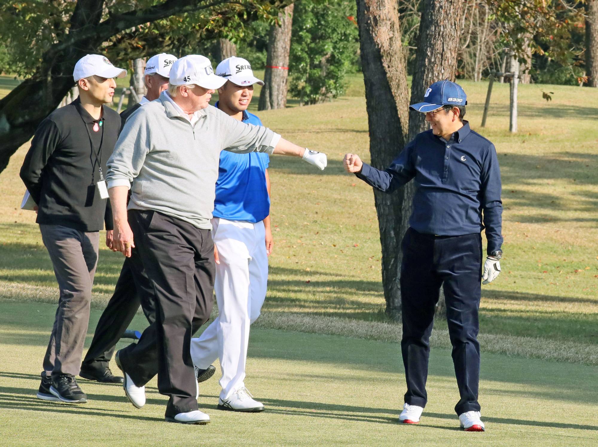 U.S. President Donald Trump fist-bumps Prime Minister Shinzo Abe as Japanese professional golfer Hideki Matsuyama looks on during a round of golf at Kasumigaseki Country Club in Kawagoe, Saitama Prefecture, in November 2017. The 92-year-old club has long been a province of the elite. | Cabinet Public Relations Office / VIA REUTERS