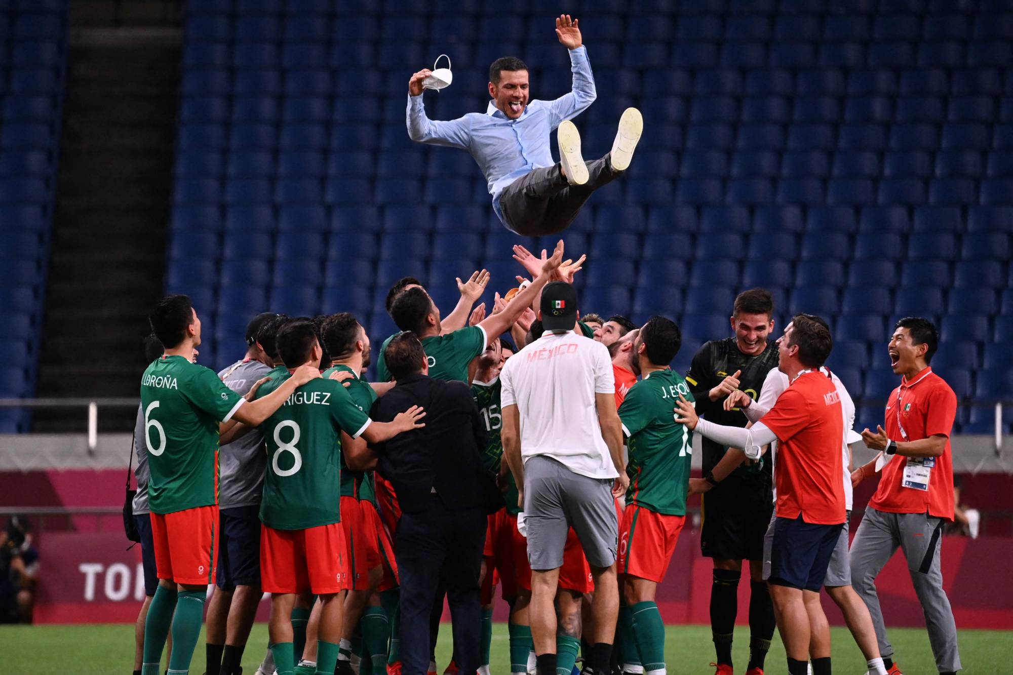 Mexico's players throw coach Jaime Lozano into the air after beating Japan to win the men's bronze medal in soccer. | AFP-JIJI
