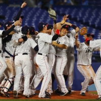 Team Japan celebrates after winning the gold medal game against the U.S. on Saturday at Yokohama Stadium. | REUTERS
