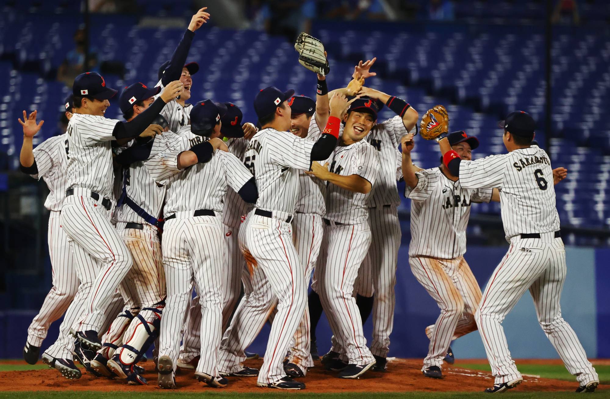 Team Japan celebrates after winning the gold medal game against the U.S. on Saturday at Yokohama Stadium. | REUTERS