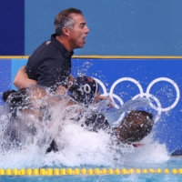 United States\' head coach Adam Krikorian is pulled into the pool by team members after they won their match again Spain in the gold medal match of women\'s water polo. | REUTERS