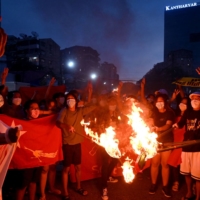 Protesters burn Myanmar flags during a demonstration against the military coup in Yangon on July 29. | AFP-JIJI