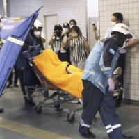 Paramedics carry an injured passenger from an Odakyu Electric Railway train on Friday in Tokyo, after a man went on a stabbing rampage inside the train. | KYODO
