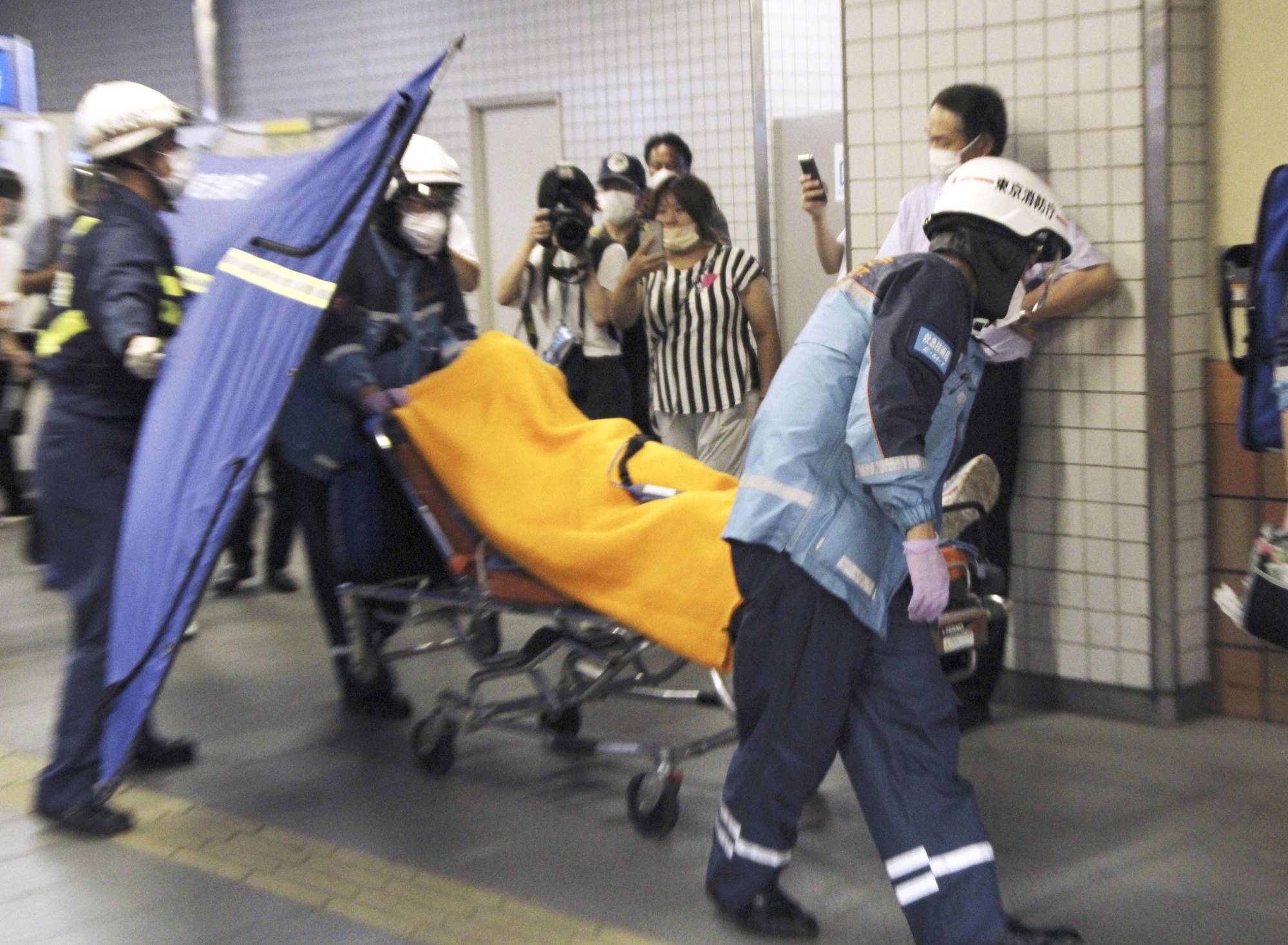Paramedics carry an injured passenger from an Odakyu Electric Railway train on Friday in Tokyo, after a man went on a stabbing rampage inside the train. | KYODO