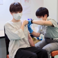 A member of staff at Tokyo Fire Department administers a dose of the Pfizer-BioNTech COVID-19 vaccine at Aoyama Gakuin University\'s Aoyama campus in Shibuya Ward, Tokyo, on Aug. 2. | STANISLAV KOGIKU /SOPA IMAGES/ VIA BLOOMBERG