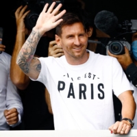 Argentinian football player Lionel Messi waves to supporters from a window after arriving in Paris on on Tuesday. | AFP-JIJI