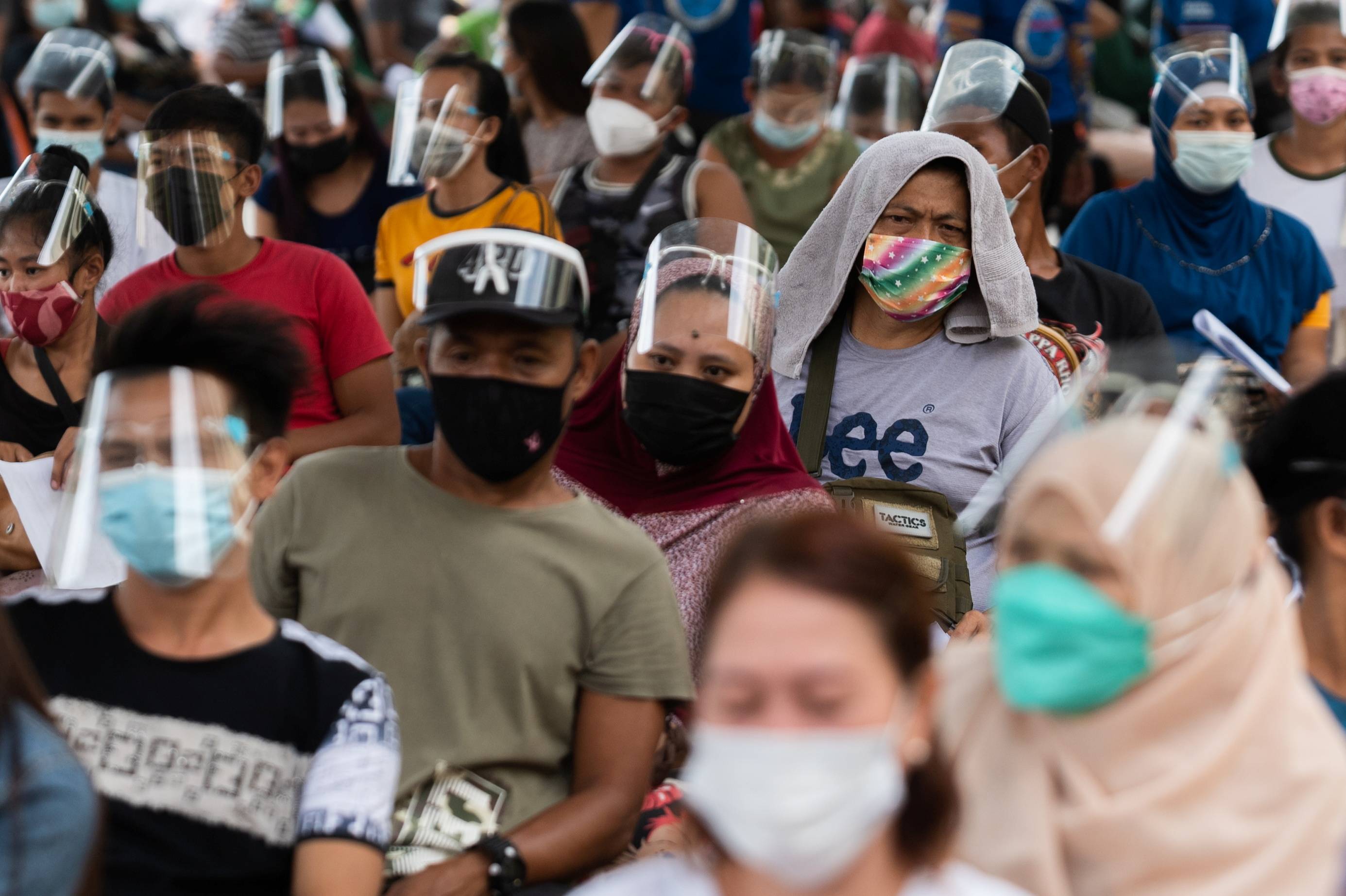 Residents line up to receive cash assistance from the government following the imposition of two-week lockdown to prevent the spread of the coronavirus delta variant in Manila last week. | REUTERS