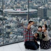 A family takes a selfie in Tokyo on Aug. 7. | REUTERS