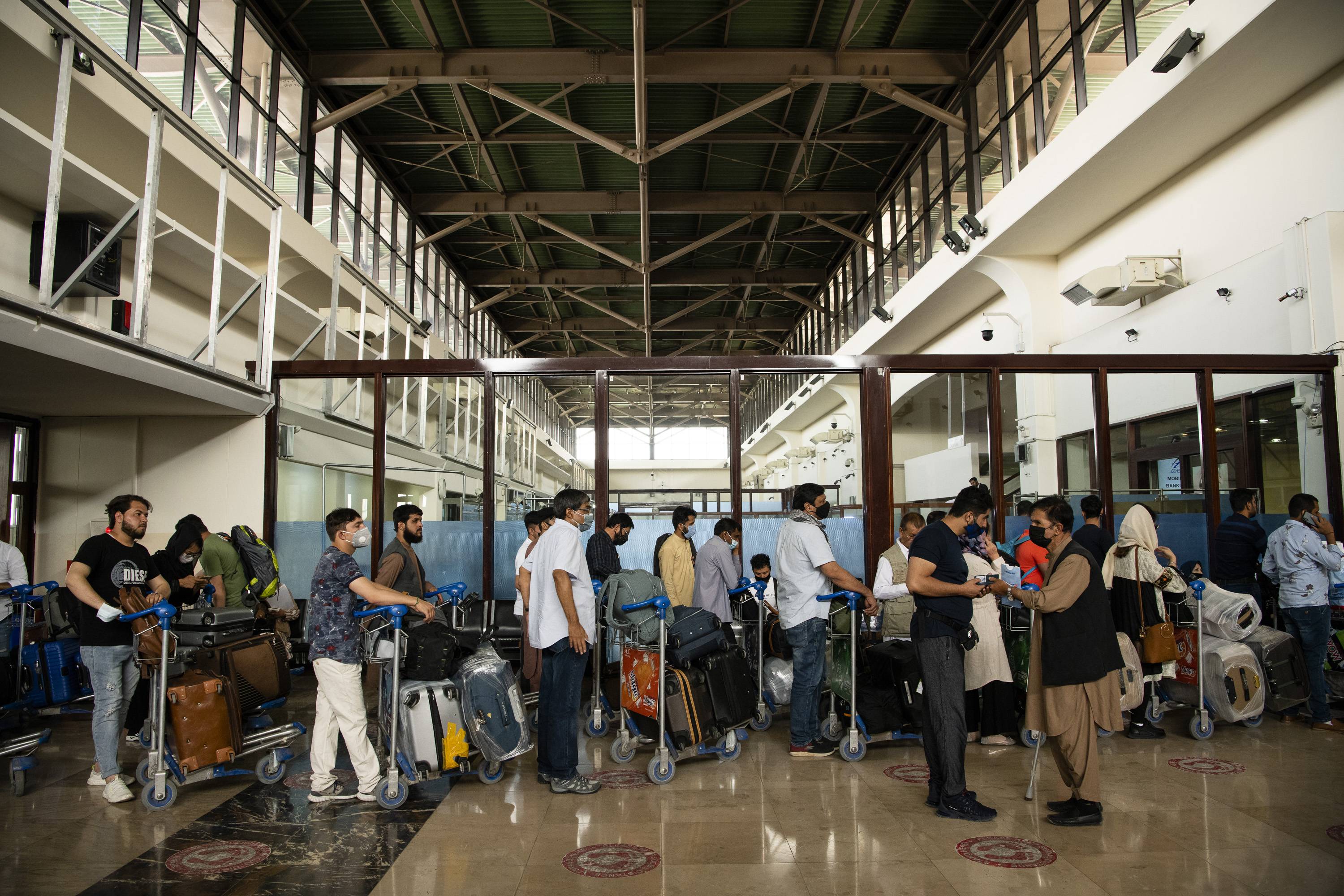 Afghans and travelers pass through checkpoints at Hamid Karzai International Airport in Kabul, ahead of the Taliban:s arrival on Sunday. | JIM HUYLEBROEK/THE NEW YORK TIMES