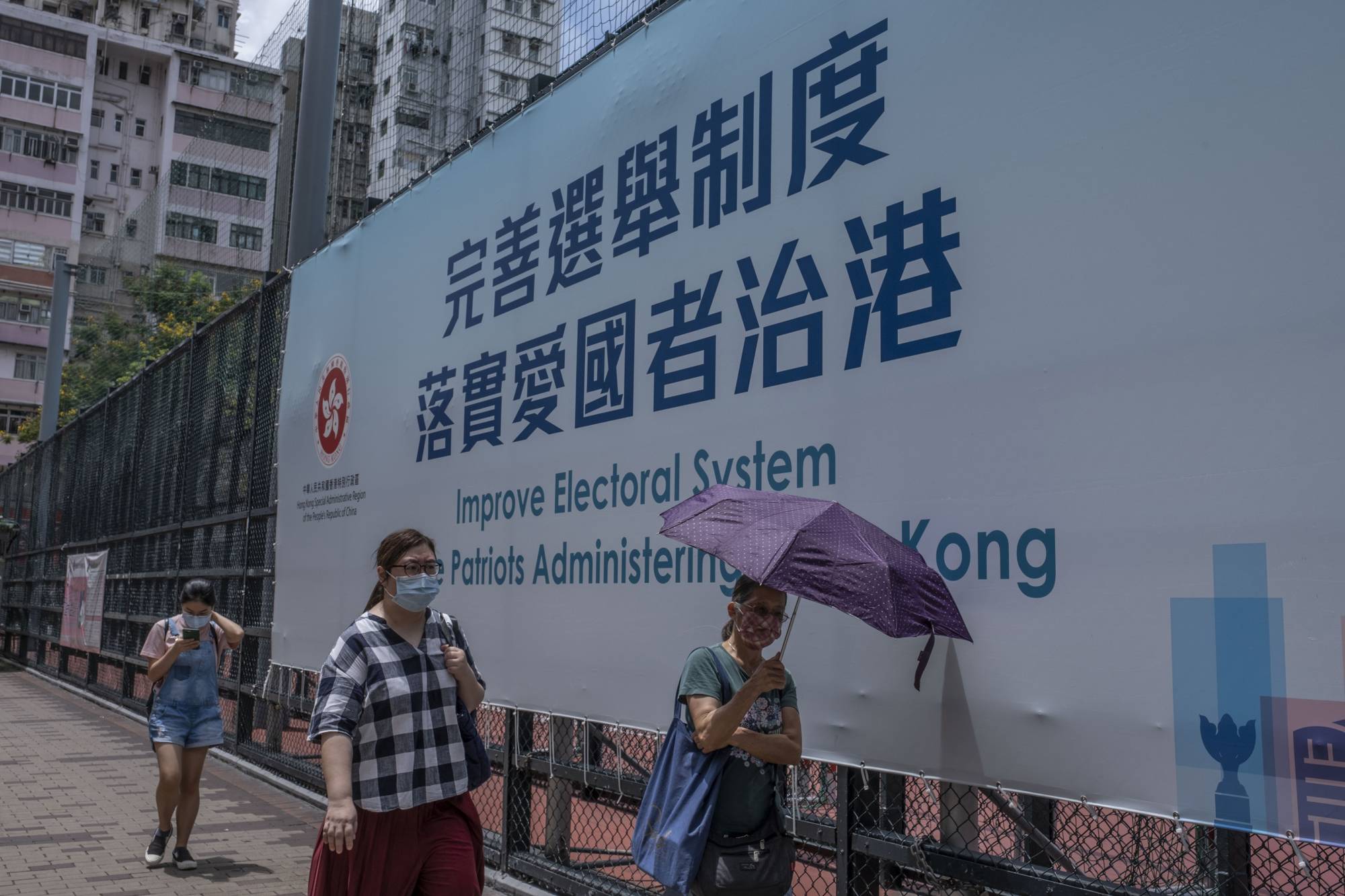 A government billboard hangs in Hong Kong, after Beijing announced in May that only patriots were allowed to run the city. When Hong Kong’s pro-democracy politicians won a resounding victory in local council elections in 2019, they inspired hopes of democratic change. Now, fears of arrest have driven most of them to quit, laying bare that dream’s dramatic collapse. | Lam Yik Fei/The New York Times