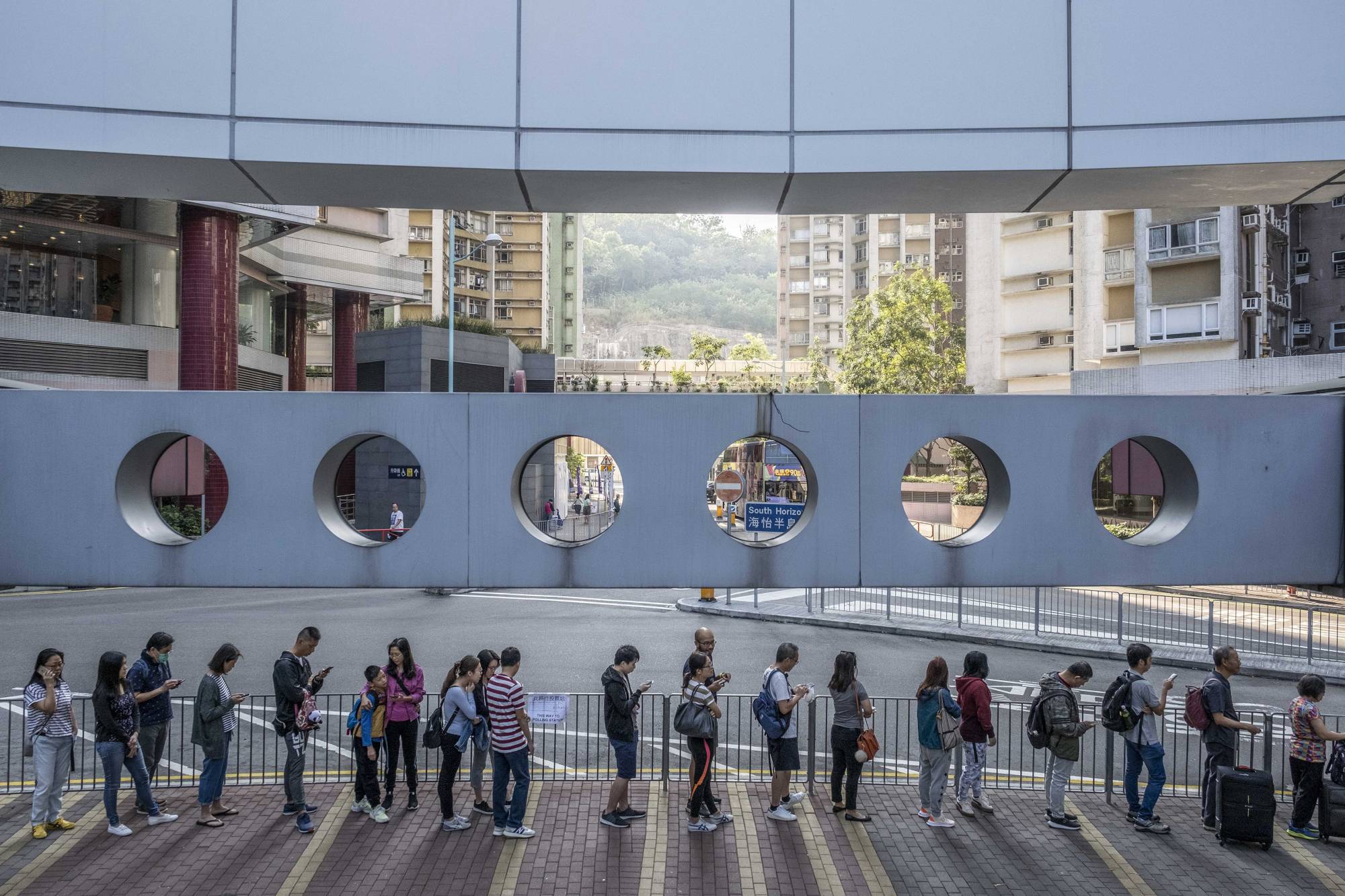 Voters wait in line at a polling station in Hong Kong in November 2019. When Hong Kong’s pro-democracy politicians won a resounding victory in local council elections in 2019, they inspired hopes of democratic change. Now, fears of arrest have driven most of them to quit, laying bare that dream’s dramatic collapse.  | LAM YIK FEI/THE NEW YORK TIMES