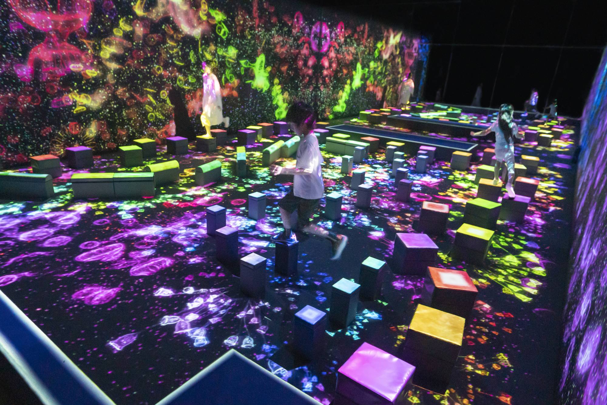 The wobbly “Balance Stepping Stones” change color when you step on them, emitting light over the digital microorganisms below. | TEAMLAB BORDERLESS, TOKYO © TEAMLAB