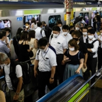 People walk out of a train in Shinjuku Station on Aug. 5. Prime Minister Yoshihide Suga asked businesses to reduce the number of commuters by 70% to cope with the continuing surge in COVID-19 infections. | AFP-JIJI