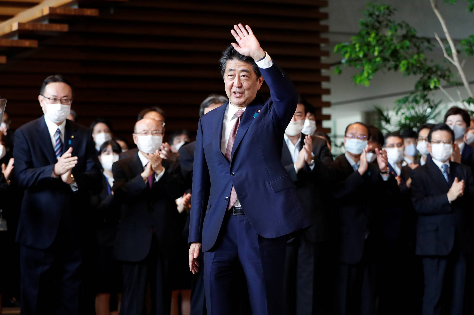 Outgoing Prime Minister Shinzo Abe waves to staff members as they bid him goodbye in Tokyo on Sept. 16, 2020. | REUTERS