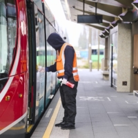 A worker sanitizes a tram at a deserted stop for the light rail network in Canberra on Aug. 13. | BLOOMBERG 