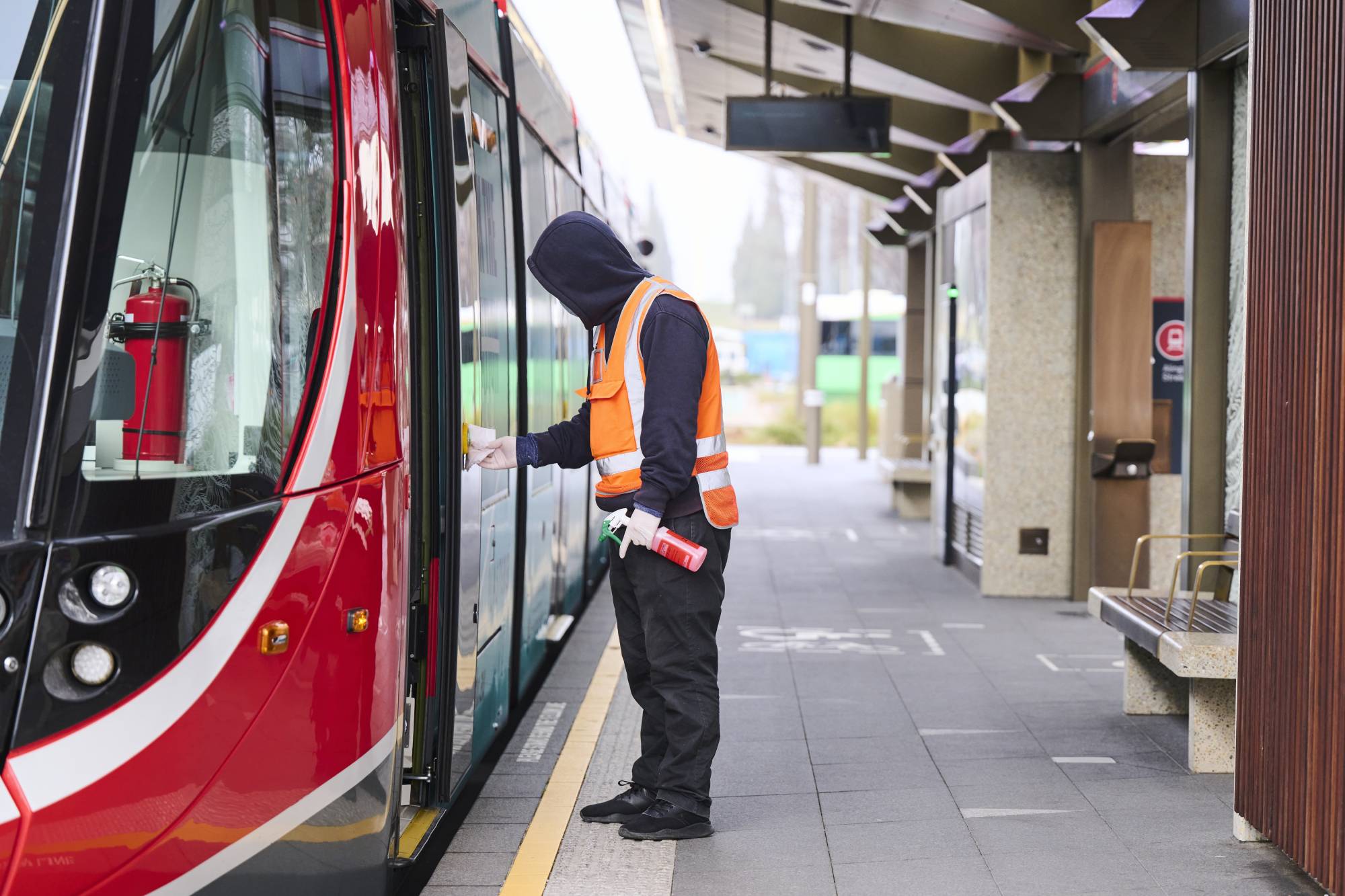 A worker sanitizes a tram at a deserted stop for the light rail network in Canberra on Aug. 13. | Bloomberg 