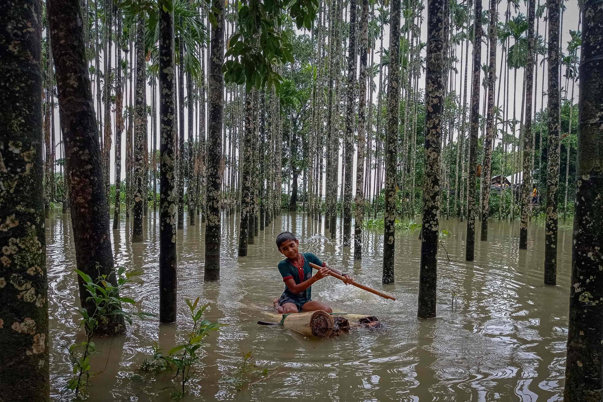 A child wades through a flooded area using a makeshift raft at Maulovir Para, Cox's Bazar, on July 30, after monsoon floods and landslides cut off more than 300,000 people in villages across southeast Bangladesh. | AFP-JIJI