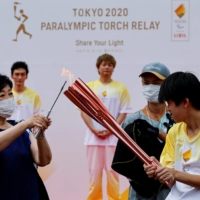 Tokyo Gov. Yuriko Koike lights the Paralympic torch during a ceremony for the Paralympic Torch Relay at Yoyogi Park in Tokyo on Tuesday. | REUTERS