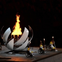 Japanese Paralympians pose in front of the lit cauldron | DAN ORLOWITZ
