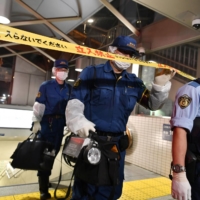 Police enter the crime scene at Tokyo Metro Co.\'s Shirokane Takanawa Station in the capital\'s Minato Ward, where a man and a woman sustained burns on Tuesday night after a suspect threw what is believed to be sulfuric acid at them and fled the scene. | KYODO