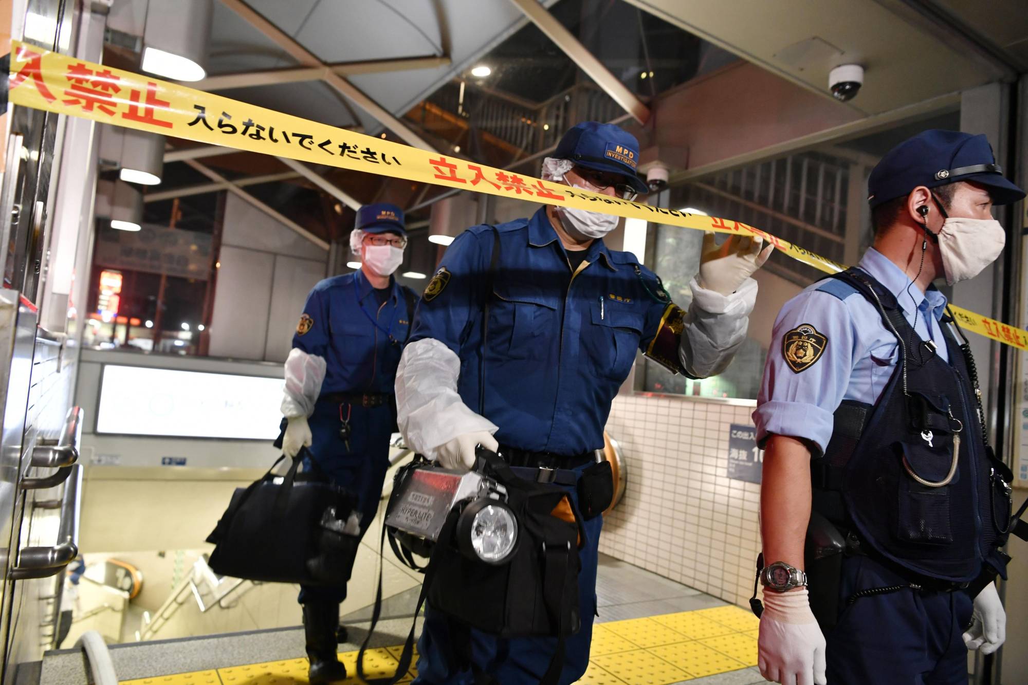 Police enter the crime scene at Tokyo Metro Co.'s Shirokane Takanawa Station in the capital's Minato Ward, where a man and a woman sustained burns on Tuesday night after a suspect threw what is believed to be sulfuric acid at them and fled the scene. | KYODO