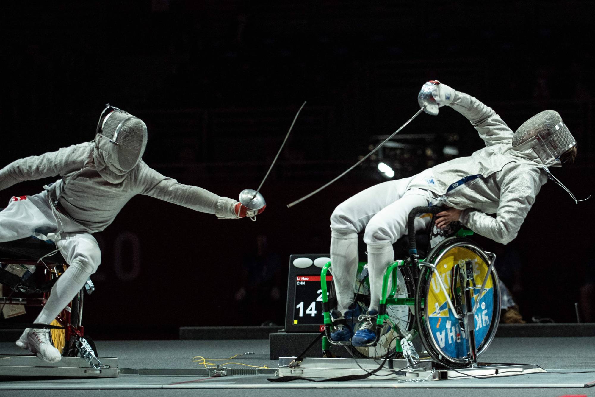 China's Li Hao (left) competes with Ukraine's Artem Manko during the men's sabre individual category A gold medal wheelchair fencing bout | AFP-JIJI