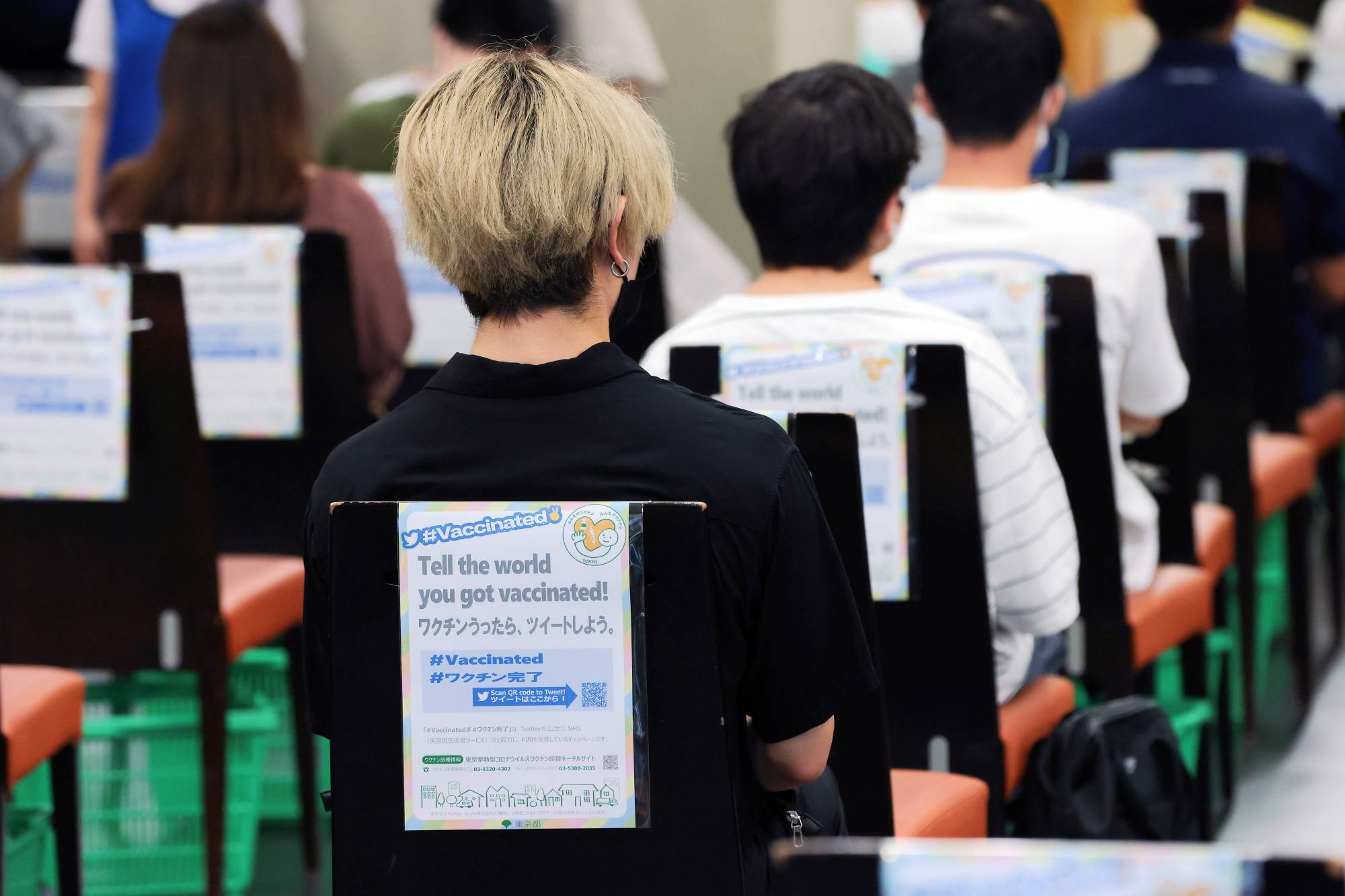 A sign encouraging visitors to tweet about their vaccination status is displayed in an observation area at a vaccination site at Aoyama Gakuin University's Aoyama campus in Tokyo on Aug. 2. | BLOOMBERG
