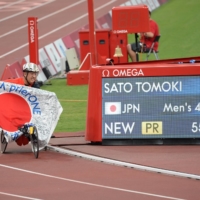 Tomoki Sato poses next to a monitor Friday showing his Paralympic record time of 55.39 seconds in the men\'s T52 400 meters  | DAN ORLOWITZ