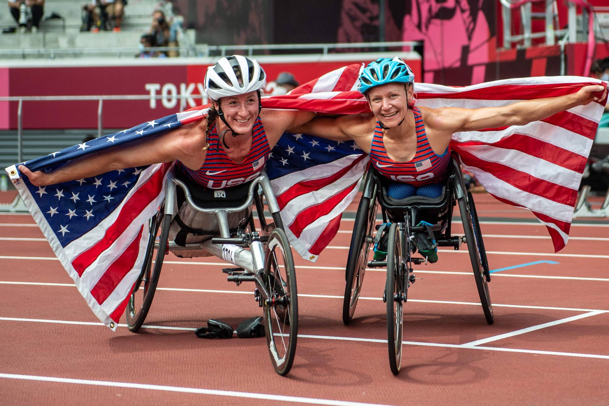 Bronze medalist Tatyana McFadden (left) and gold medalist Susannah Scaroni celebrate after the women's T54 5000 meters. | AFP-JIJI