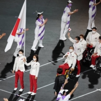 Koyo Iwabuchi (left) and Mami Tani carry the flag during the opening ceremony of the Tokyo Paralympics.  | REUTERS