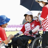 Archery athlete Aiko Okazaki receives a massage under a parasol as she cools herself with an ice bag at the Tokyo Paralympics on Friday.  | KYODO