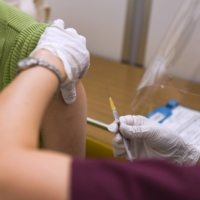 A health care worker administers a dose of the Moderna Inc. COVID-19 vaccine at a mass vaccination site in Saitama on Aug. 23. | BLOOMBERG