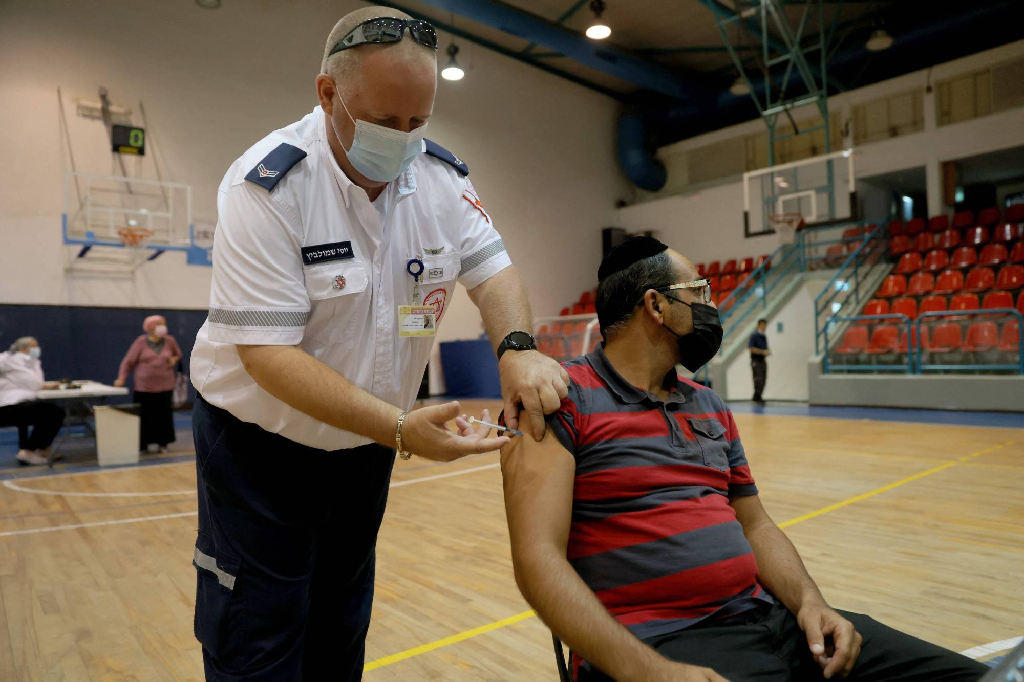 A paramedic administers a booster shot of the Pfizer-BioNTech COVID-19 in Holon, Israel, on Aug. 24. | AFP-JIJI