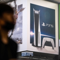 A pedestrian wearing protective mask walks past a billboard advertising Sony Corp.\'s PlayStation 5 video game console in Hong Kong. China’s strict limits on how long minors can play online video games just got stricter. Chinese children and teenagers are banned from online gaming on school days, and limited to one hour a day on weekend and holiday evenings under government rules issued Monday. | BLOOMBERG