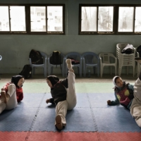 Zakia Khudadadi (left) stretches before training at the Afghan National Taekwondo Federation gym in Kabul in March 2016. | ADAM FERGUSON / THE NEW YORK TIMES