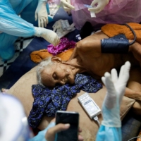 Nuan, a 93-year-old COVID-19 patient, is treated by a volunteer in Bangkok on Aug. 5.  | REUTERS
