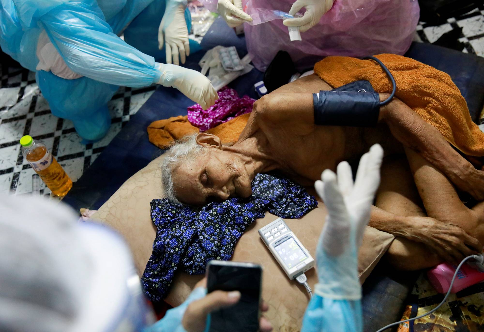 Nuan, a 93-year-old COVID-19 patient, is treated by a volunteer in Bangkok on Aug. 5. | Reuters