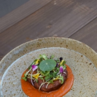A contemporary reworking of a traditional deep-fried snack, aloo pakoda. The potato and chickpea patty comes on a homemade mustard seed \"ketchup\" sauce topped with edible flowers. | ADI RESTAURANT
