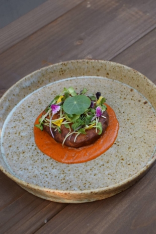 A contemporary reworking of a traditional deep-fried snack, aloo pakoda. The potato and chickpea patty comes on a homemade mustard seed 'ketchup' sauce topped with edible flowers. | ADI RESTAURANT 