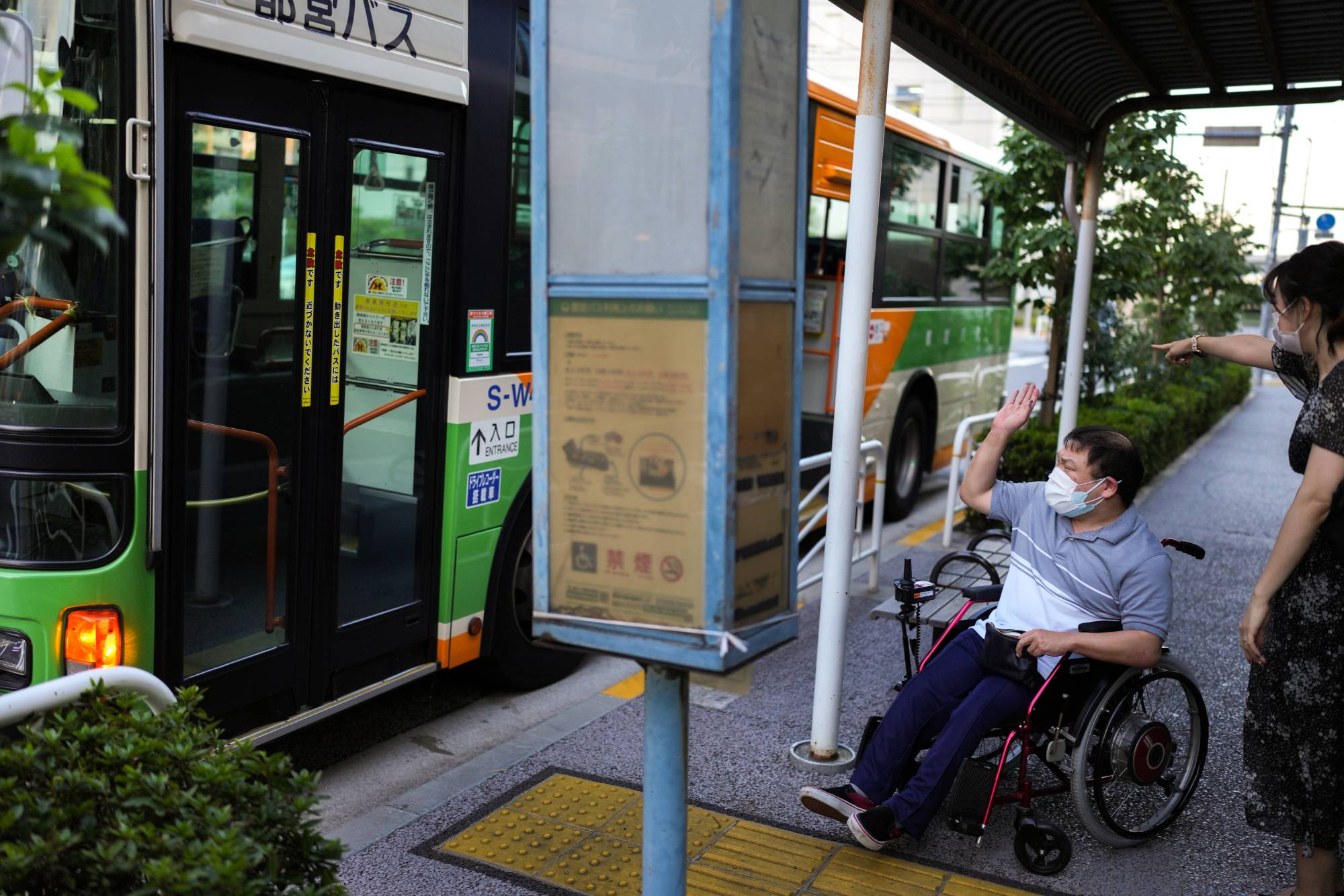 Yuto Hirano, a volunteer for the Paralympics, navigates boarding a bus in Tokyo on Aug. 23. Tokyo has made improvements to its accessibility, but people with disabilities still encounter barriers daily. | Chang W. Lee/The New York Times