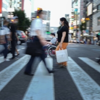 Yuto Hirano, a volunteer for the Paralympics, rolls through a crosswalk on his way to a haircut appointment in Tokyo on Aug. 23. Tokyo improved its infrastructure before the delayed 2020 Games, but activists wonder how long the focus will continue in a country with a long history of excluding people with disabilities.  | CHANG W. LEE/THE NEW YORK TIMES