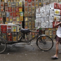 A man loads empty containers of edible oil onto a tricycle in Kolkata. | REUTERS