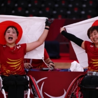 Sarina Satomi (left) and Yuma Yamazaki celebrate after winning Paralympic gold in the badminton women\'s doubles WH competition on Sunday at Yoyogi National Stadium. | REUTERS
