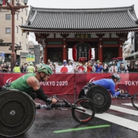 Ireland\'s Patrick Monahan (left) and RPC\'s Vitalii Gritsenko race past Kaminarimon in Tokyo\'s Asakusa district on Sunday as bystanders watch during the men\'s T54 marathon. | REUTERS